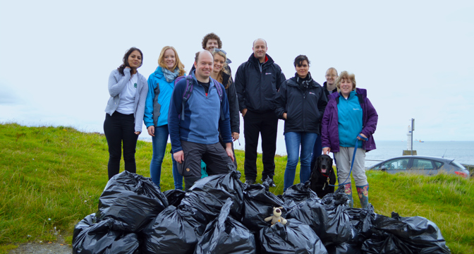 A group of people standing next to bunch of bin bags